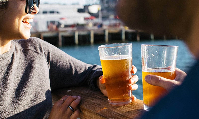couple-enjoying-beer-near-ocean